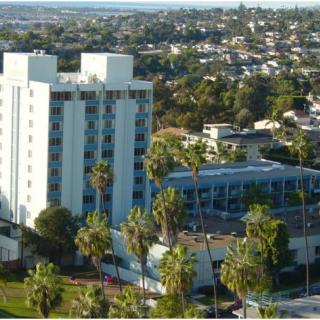 Aerial view of a residential building surrounded by palm trees in an urban area.