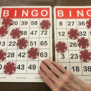 A close-up view of two Bingo cards with several marked numbers, showcasing an ongoing game.