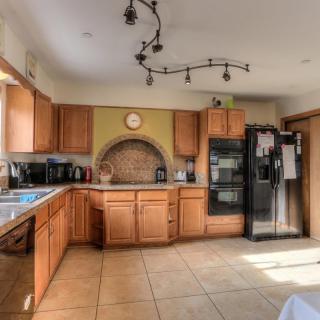 A spacious modern kitchen featuring wooden cabinets, a double-door refrigerator, and ample natural light.