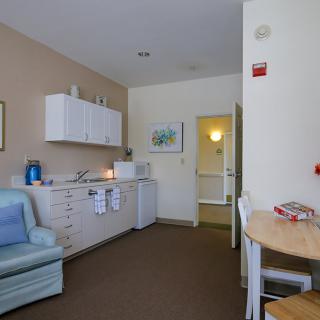 A cozy living area with a small kitchenette, featuring a sofa, table, and chairs.