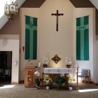 A church interior featuring an altar with a cross and religious decorations.