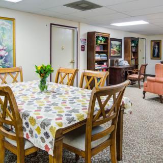 A cozy dining area with a table, chairs, and a bookshelf in a warmly decorated room.