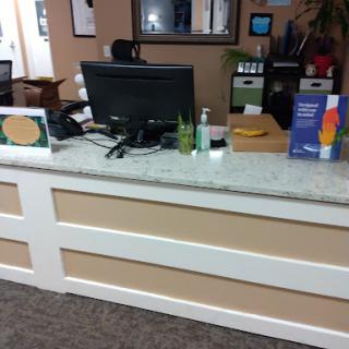 A view of a reception desk in an office setting, featuring a computer and various informational materials.