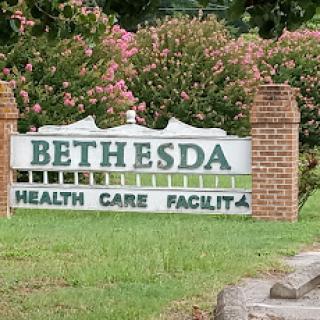 Sign for Bethesda Health Care Facility surrounded by greenery.
