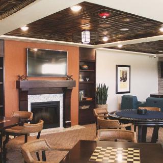 A modern living room with a fireplace, television, and various seating options arranged around tables.
