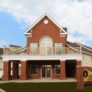 A brick building with a prominent entrance and large windows, featuring a sign indicating it's a library.