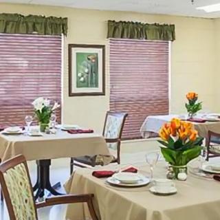 A neatly arranged dining room with tables set for a meal and floral centerpieces.