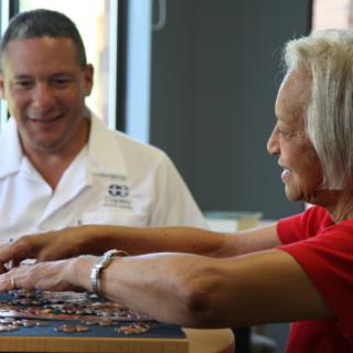 Two individuals engaging in a friendly puzzle activity indoors.