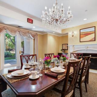 An elegant dining room with a beautifully set table, a chandelier overhead, and decorative elements including flowers and artwork.