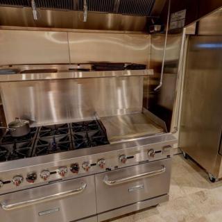 A commercial kitchen setup with a stainless steel stove and oven.