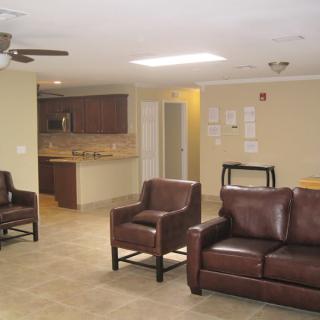 A spacious living area with leather chairs and couches, leading into a modern kitchen.