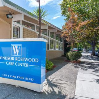 Entrance to Windsor Rosewood Care Center with a prominent blue sign and surrounding greenery.