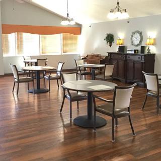 A modern dining area with hardwood floors and several tables and chairs set up for seating.
