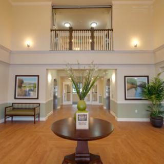 A spacious and elegant lobby featuring a central table with floral decor, framed artwork, and welcoming ambiance.