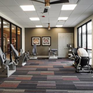 A modern gym with various exercise equipment and large windows.