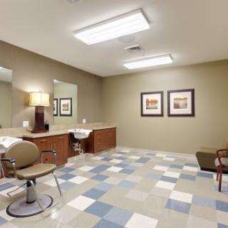 A spacious and well-lit hair salon area featuring modern furniture and a stylish design.