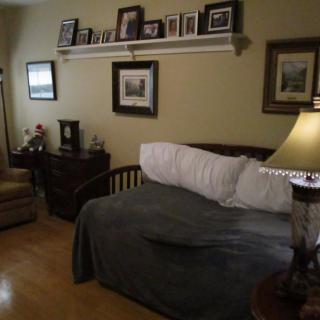 A cozy bedroom with a couch, adorned with picture frames and a lamp.