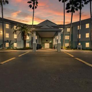 A hotel building with palm trees at sunset.