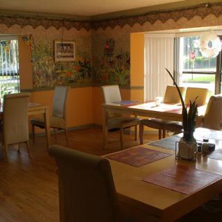 A cozy restaurant dining area with tables and chairs, filled with natural light.