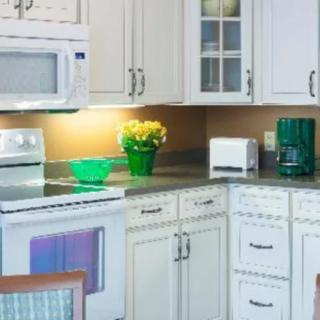 A modern kitchen with white cabinets and various appliances including a microwave, stove, coffee maker, and toaster.