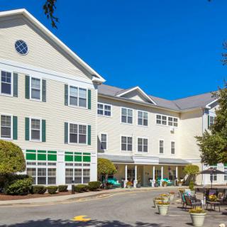 A residential apartment building with multiple stories and a well-maintained exterior on a clear day.