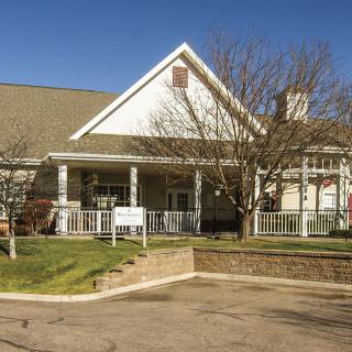 A large residential house with a spacious front porch and surrounding trees.
