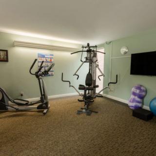 A home gym setup featuring an elliptical machine, a multi-gym station, and yoga accessories.