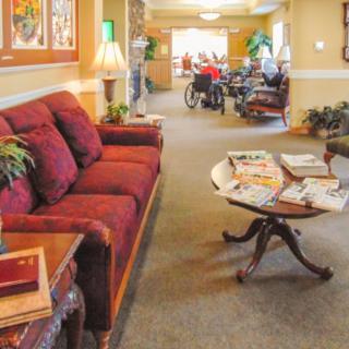 A cozy living room area with a red couch, coffee table topped with magazines, and decorative elements in a communal setting.