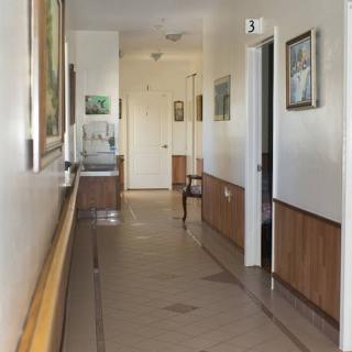 A well-lit indoor hallway with paintings on the walls and wood paneling.