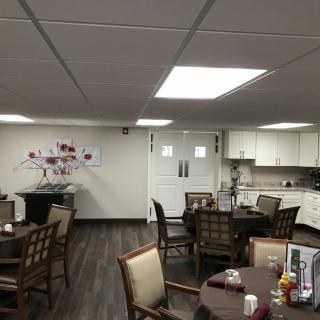 A cozy dining room with multiple tables and chairs, a small kitchen area, and decorative wall art.