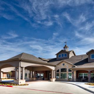 A large residential building with a covered entrance and a clear blue sky.