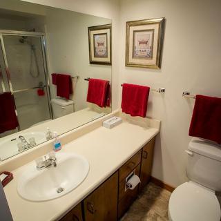 A clean bathroom with a large mirror, red towels, and framed artwork.