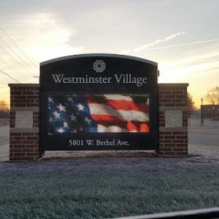 Entrance sign of Westminster Village featuring an American flag.