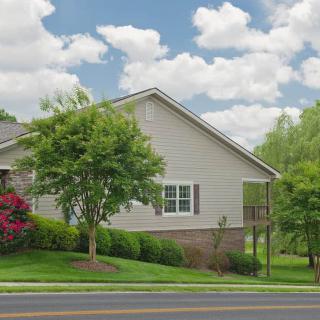 A suburban house with a well-maintained yard and trees, set against a cloudy sky.