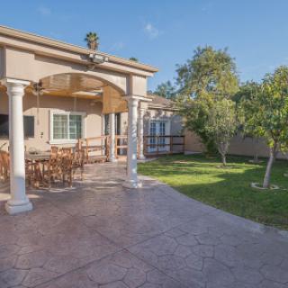 A spacious patio area with dining furniture, surrounded by a lush garden.