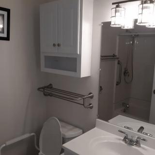 A modern bathroom featuring a sink, toilet, and shower with overhead lighting.