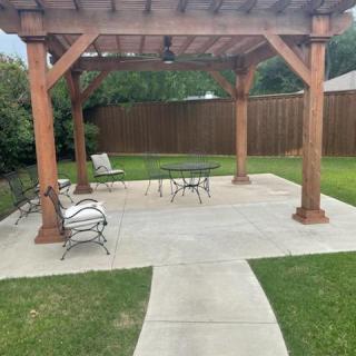 A backyard patio with a pergola and outdoor furniture.