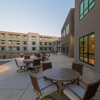 An outdoor patio area with tables and chairs adjacent to a modern building.