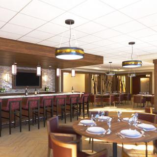 A spacious restaurant interior featuring a bar counter and elegantly set dining tables.