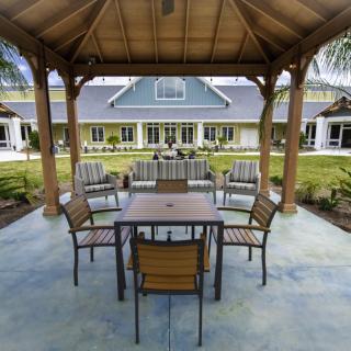 A cozy outdoor seating area under a gazebo with a view of a modern building in the background.