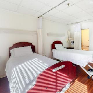 A bright and clean hospital room featuring two beds with a modern design.