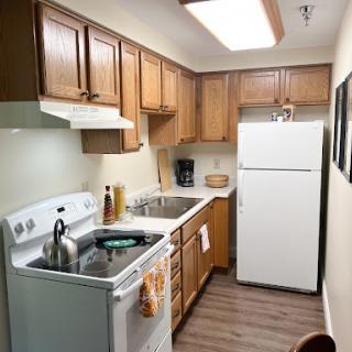 A well-organized kitchen featuring wooden cabinets, essential appliances, and a clean countertop.
