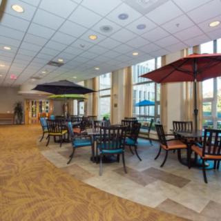 A spacious indoor seating area with tables, chairs, and colorful umbrellas.