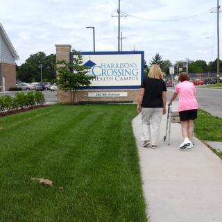 Two people walking towards a nursing home entrance.