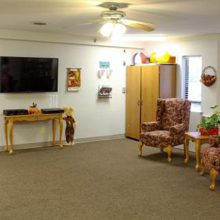 A cozy living room with a television, armchairs, and various decorations.