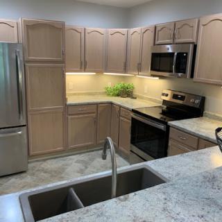 A modern kitchen featuring light wooden cabinets, stainless steel appliances, and a spacious countertop.