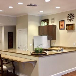 A modern kitchen featuring a countertop with decorative items, white appliances, wall-mounted artwork, and recessed lighting.