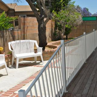 A sunny patio area with white furniture and a fenced garden.