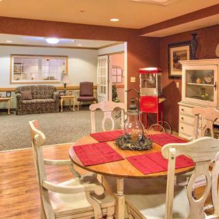 A cozy interior featuring a dining area with a wooden table and red placemats, adjacent to a living room with comfortable seating.