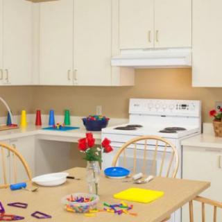 A kitchen with a dining table set for crafts, featuring colorful cups and a vase of flowers.
